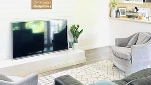 Uma sala de estar moderna com televisão de tela plana, lareira e um aviso fixado com diversos destinos.