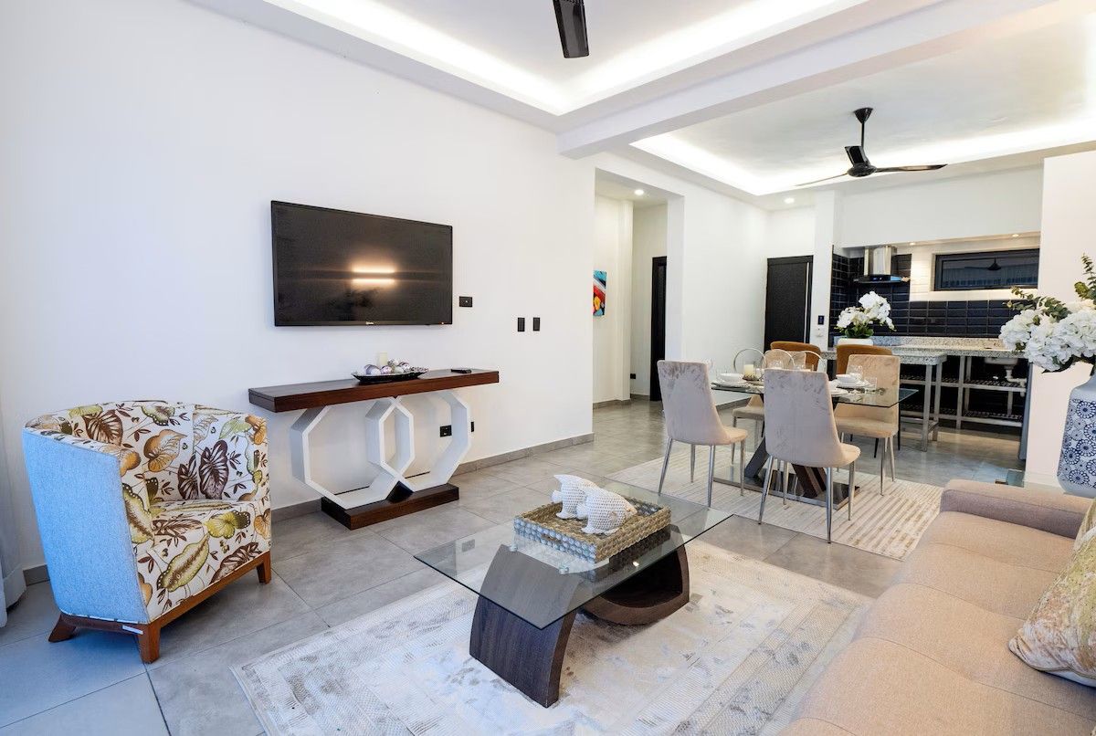 A modern living room with a flat-screen TV, a glass coffee table, and a sofa.