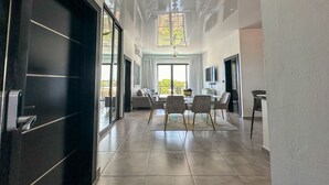 A spacious living area with a large window, a dining table, and a sofa.