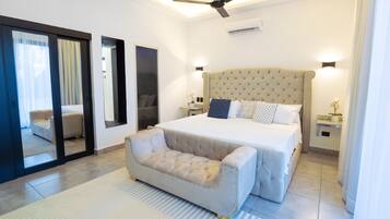 Une chambre moderne avec un grand lit, un canapé, un ventilateur de plafond et une porte-fenêtre coulissante donnant sur un balcon.