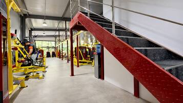 A gym with exercise equipment, a staircase, and a concrete floor.