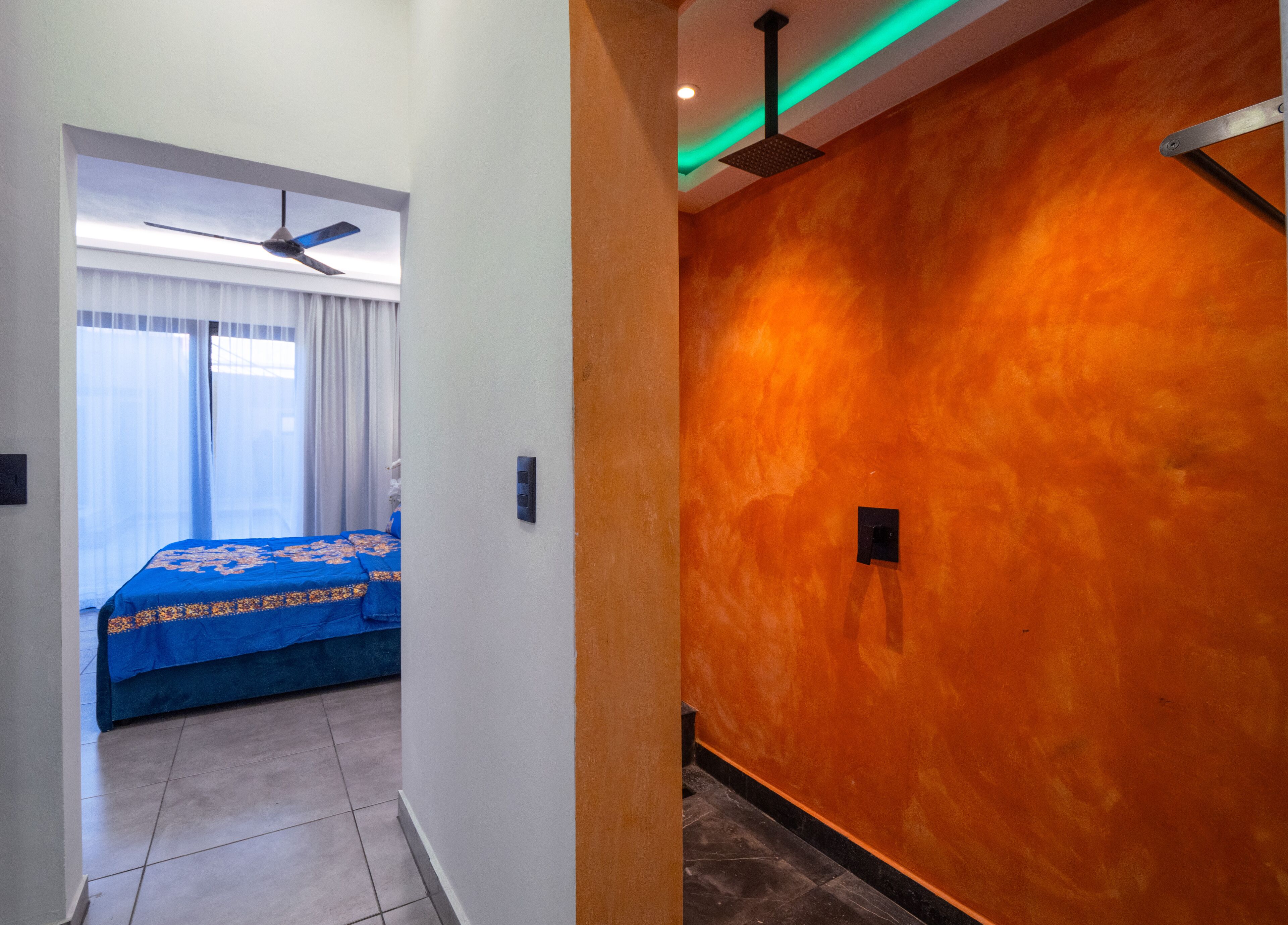 Une chambre d’hôtel avec un lit, un ventilateur de plafond et une salle de bain avec douche.