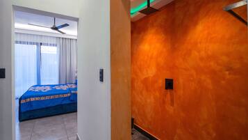 Une chambre d’hôtel avec un lit, un ventilateur de plafond et une salle de bain avec douche.