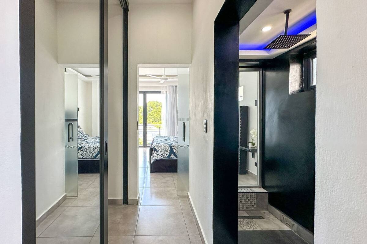 A modern hotel corridor with a glass door leading to a balcony with a bed.