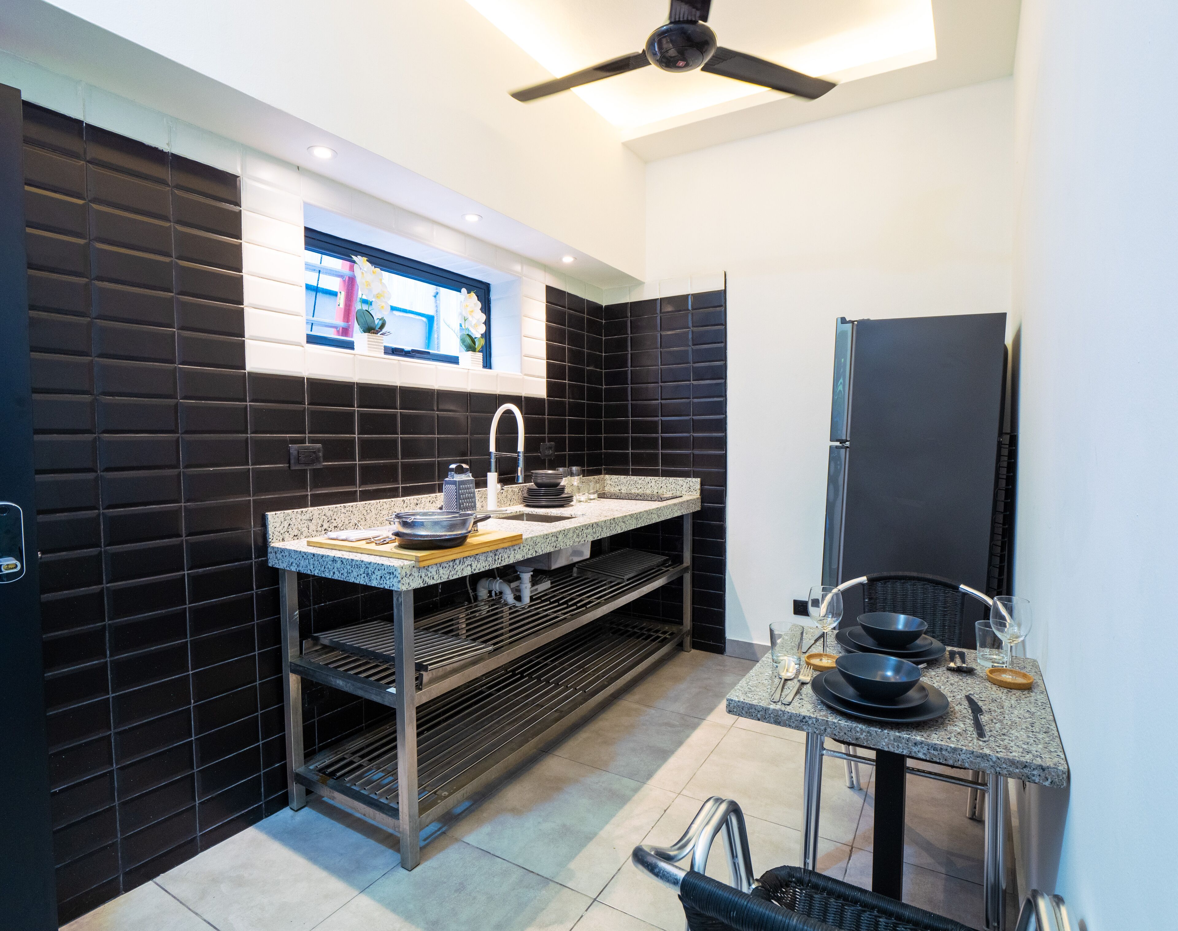 Una cocina moderna con protector de salpicaduras de azulejos negros, electrodomésticos de acero inoxidable y horno empotrado.