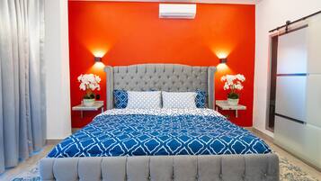 Un dormitorio con una cama grande, dos mesitas de noche con lámparas y una pared de acento roja.