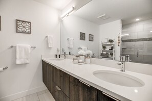 Een moderne badkamer met twee wastafels, een grote spiegel en decoratieve wandkunst.