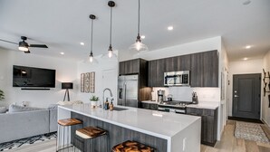 A modern kitchen with a central island, bar stools, and a built-in oven.