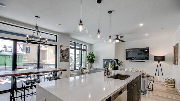 A modern kitchen with a large island, pendant lighting, and a view of the city.