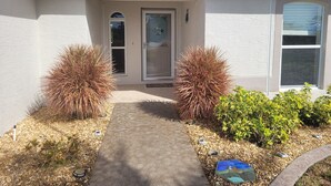 A house with a front entrance, a pathway leading to the door, and two shrubs flanking the entrance. - 2 Bed 2 Bath Heated Pool Vacation House, Very Private (Rotonda West)