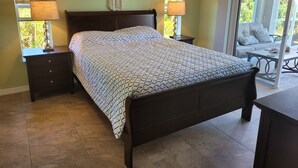 A bedroom with a bed, two bedside tables with lamps, a window with blinds, and a view of a balcony. - 2 Bed 2 Bath Heated Pool Vacation House, Very Private (Rotonda West)