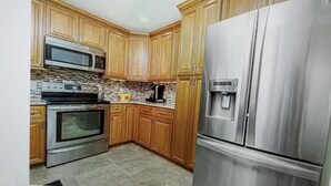 A kitchen with wooden cabinets, a stainless steel refrigerator, a microwave, and an oven. - 2 Bed 2 Bath Heated Pool Vacation House, Very Private (Rotonda West)