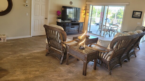 A living room with wicker furniture, a flat-screen TV, and a sliding glass door leading to an outdoor patio. - 2 Bed 2 Bath Heated Pool Vacation House, Very Private (Rotonda West)