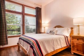 Una camera da letto con un letto, due comodini, una finestra con persiane e tende.