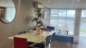 Un comedor moderno con una mesa de vidrio, sillas rojas y un espejo grande.