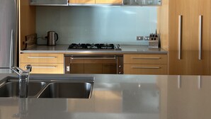 Una cocina moderna con electrodomésticos de acero inoxidable, armarios de madera y una isla central con un lavabo.