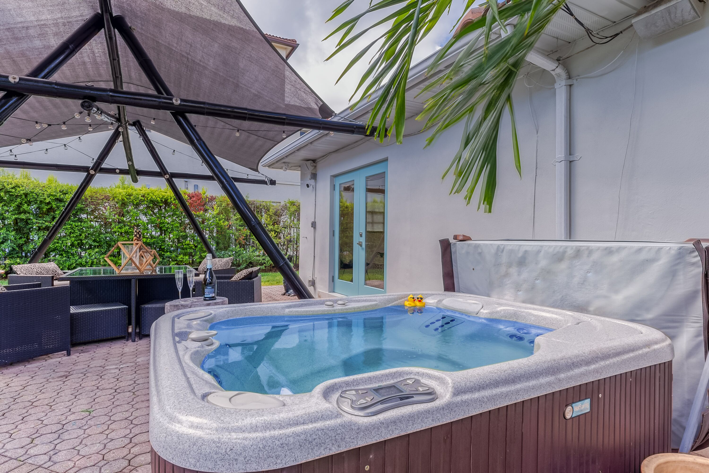 Ein Whirlpool mit Bedienfeld, umgeben von Gartenmöbeln und einer überdachten Sitzgelegenheit.