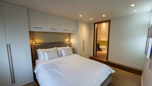 A modern bedroom with a large bed, built-in wardrobe, and a mirror. - Fulham 2-Bed | Both En-Suite | Private Patio | Sleeps 5 (London)
