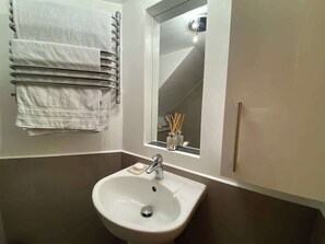 A bathroom with a sink, mirror, towel rack, and toiletries.
