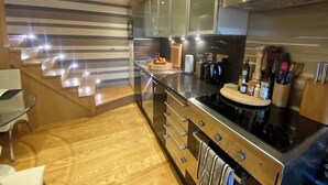 A modern kitchen with stainless steel appliances, wooden cabinets, and a wooden staircase. - Fulham 2-Bed | Both En-Suite | Private Patio | Sleeps 5 (London)