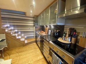 Una cocina moderna con electrodomésticos de acero inoxidable, armarios de madera y una escalera de madera.