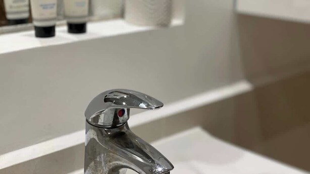 A bathroom with a modern faucet, a shelf with toiletries, and a roll of toilet paper. - Fulham 2-Bed | Both En-Suite | Private Patio | Sleeps 5 (London)