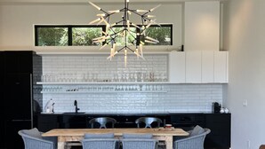 Een moderne keuken met een groot eiland, witte kasten en een bijzondere kroonluchter.
