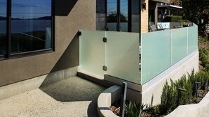 Een modern huis met een groot raam, een balkon en een kleine tuin.