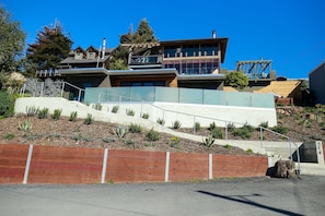 A modern multi-story house with a prominent staircase, a wooden deck, and a well-maintained garden. - A spectacular home with a three bridge view out the Golden Gate. (Richmond)