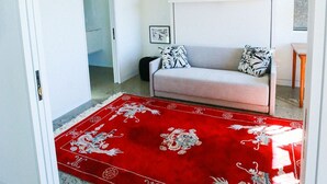 Een kamer met een rood tapijt, een bank en een klein tafeltje.