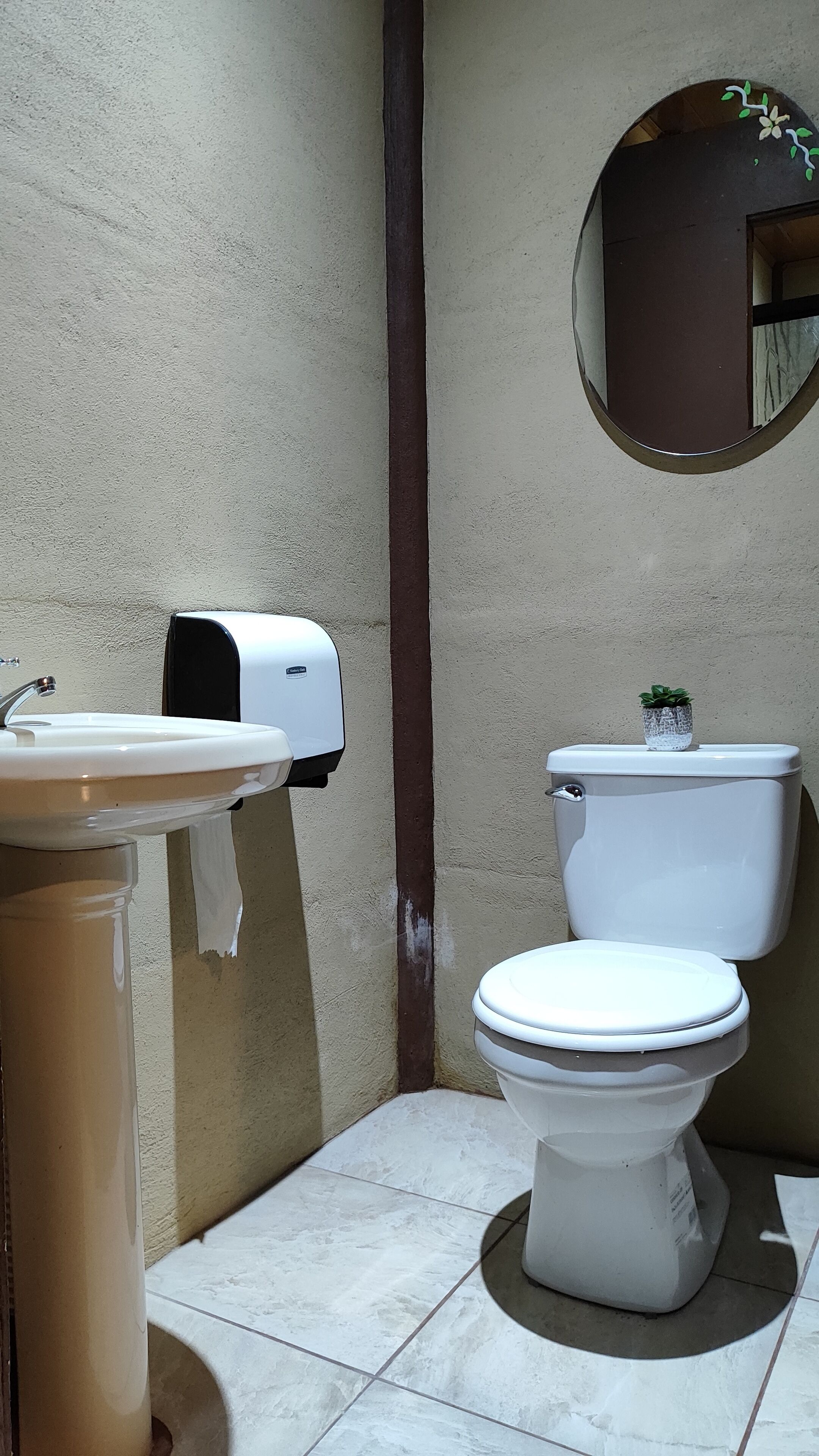 Un baño con inodoro, lavabo y dispensador de toallas de papel.