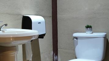 Un baño con inodoro, lavabo y dispensador de toallas de papel.