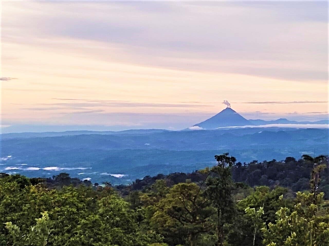 Un paysage de montagne avec un sommet imposant, entouré d’une forêt dense et offrant une vue sur l’océan.