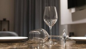 Une table en marbre avec deux assiettes et un verre à vin brisé.