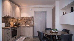 Une cuisine moderne avec des meubles en bois, un four encastré et un évier. On y trouve une table à manger avec des chaises, et une petite plante en pot posée dessus.