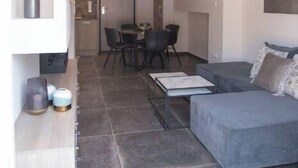 Un salon moderne avec un canapé gris, une table basse et un coin repas comprenant des chaises et une table.