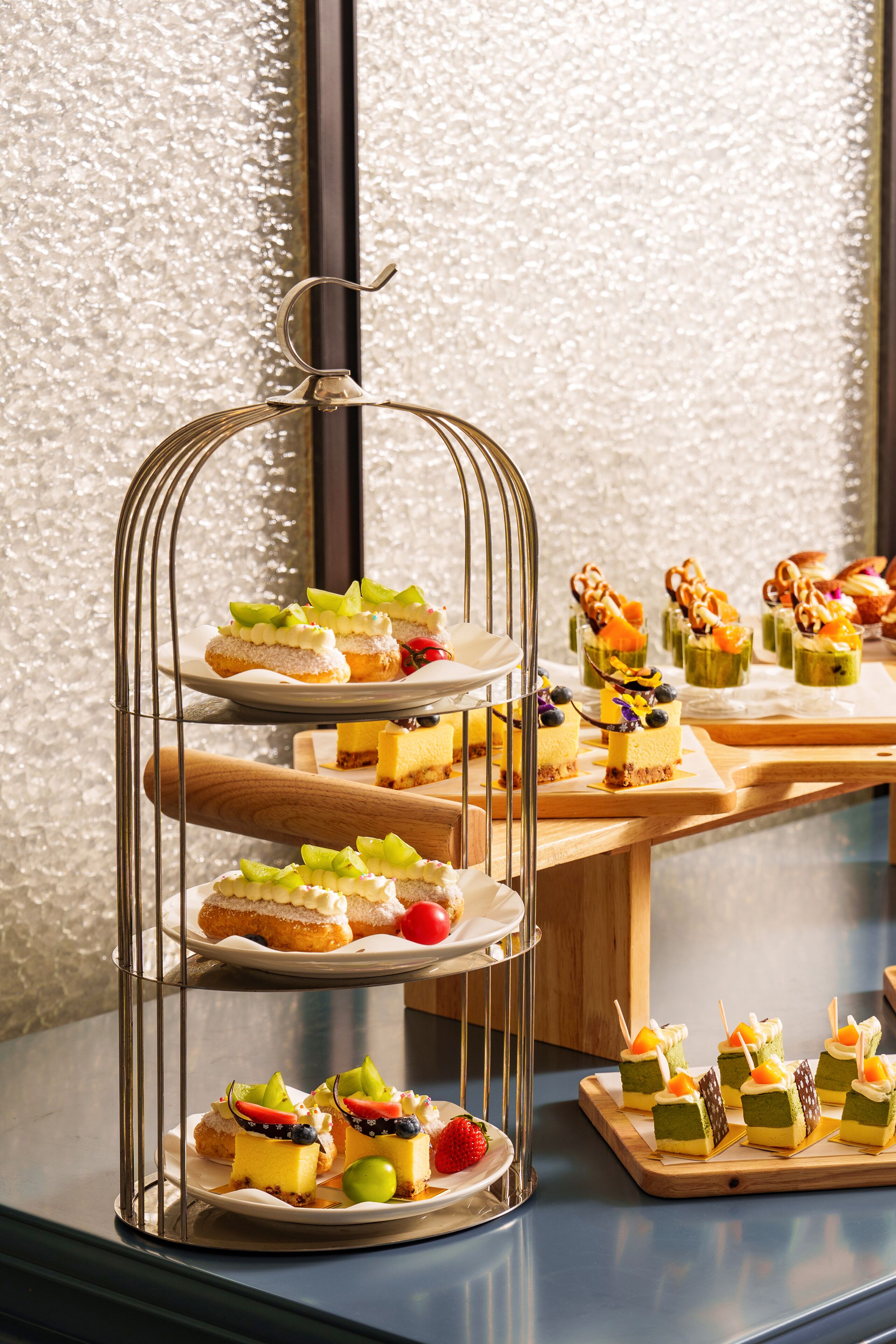 Une présentation de desserts à plusieurs niveaux, comprenant divers pâtisseries et gâteaux, le tout mis en valeur par un mur à texture.