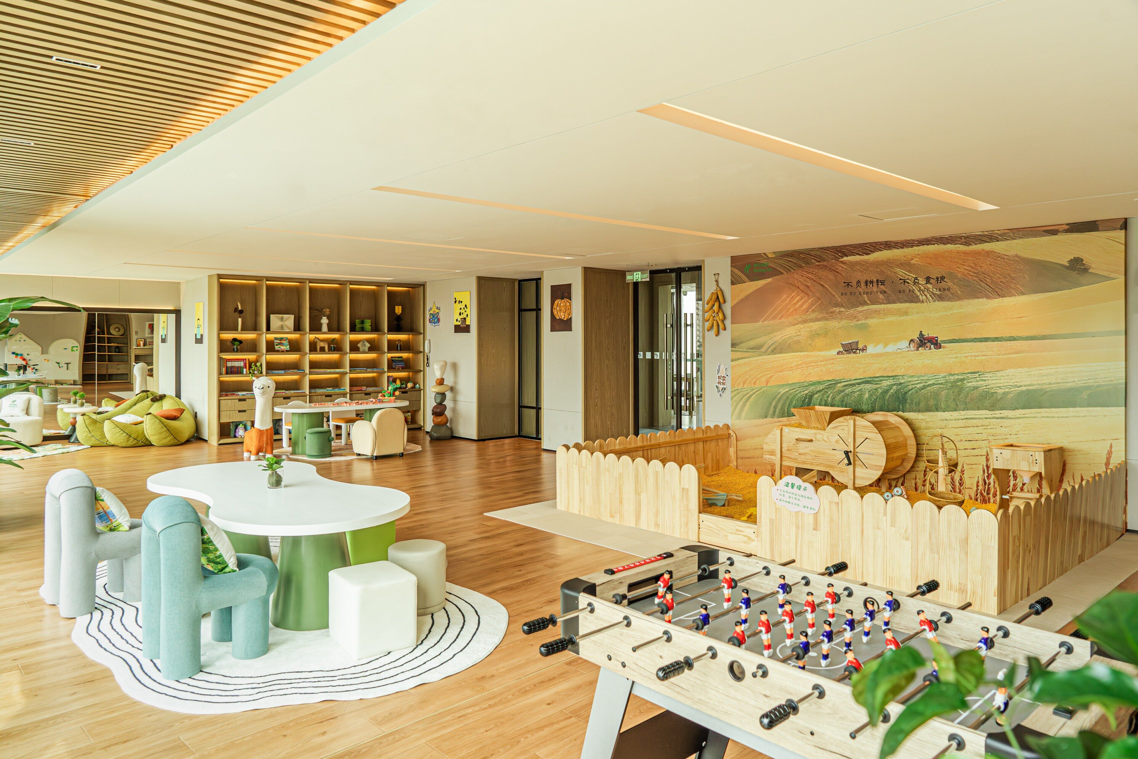 A modern interior with a foosball table, a wooden playhouse, and a mural.
