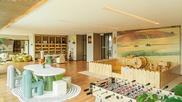 A modern interior with a foosball table, a wooden playhouse, and a mural.