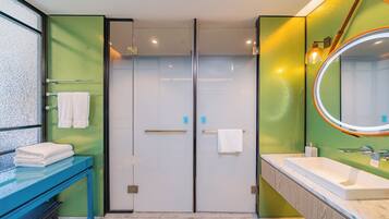 Un baño moderno con cabina de ducha de vidrio, tocador azul y un espejo grande.