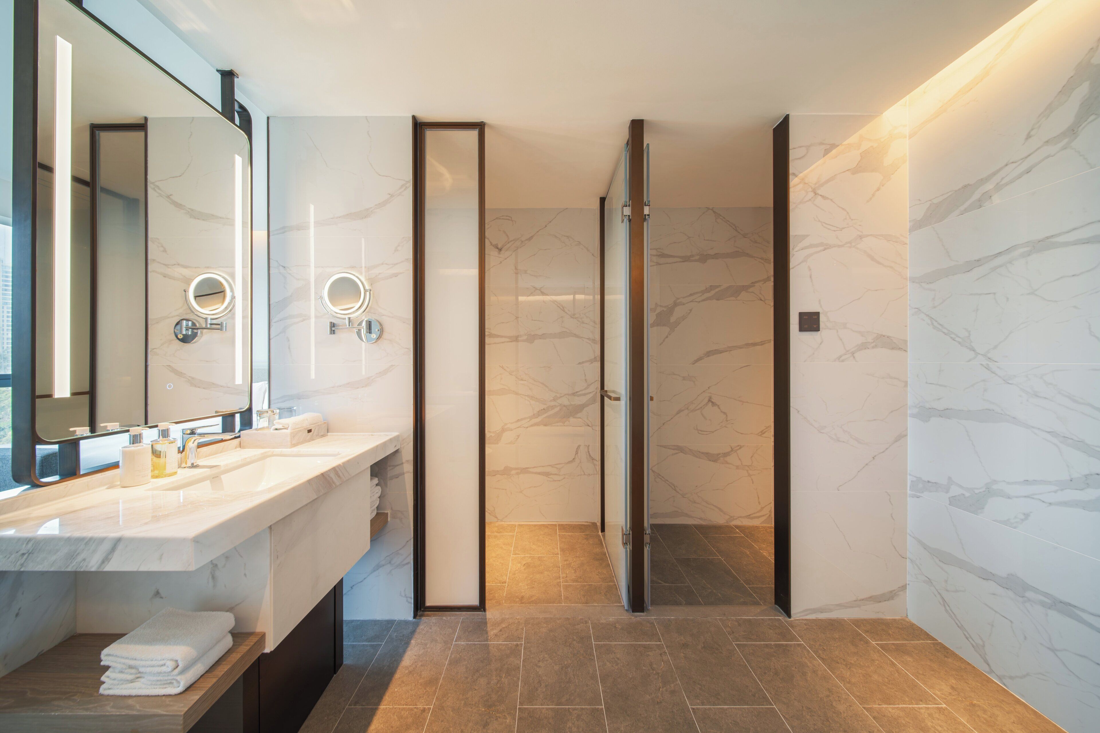 A modern bathroom with a large mirror, a sink, and a shower area.