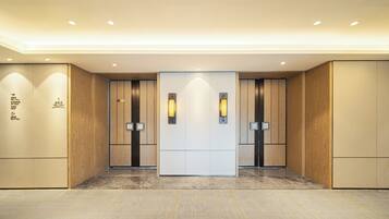 A modern elevator with wooden paneling and illuminated wall sconces.
