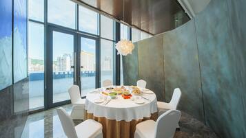 Comedor con una mesa redonda para seis personas, ventanas amplias y vistas a edificios.