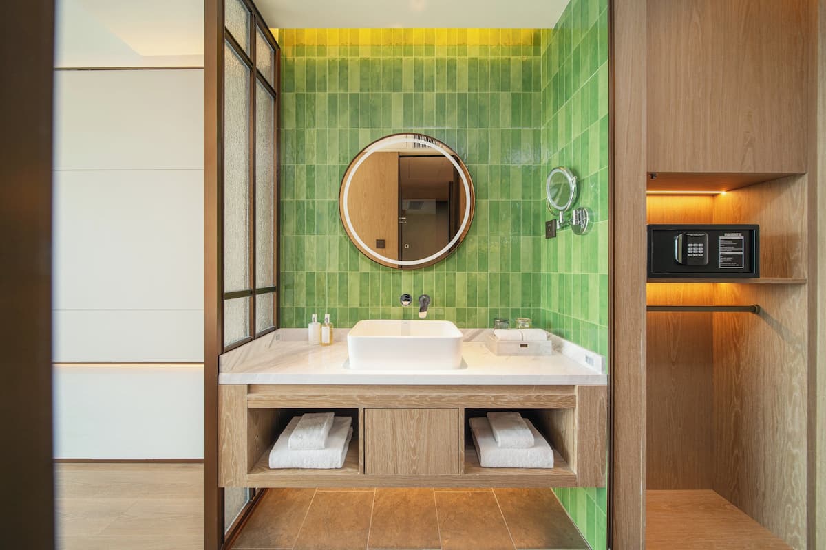 A modern bathroom with a large mirror, two sinks, and a built-in towel rack.