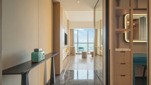 Un pasillo moderno de hotel con un escritorio de madera, un adorno azul verdoso y vistas al cielo a través de amplias ventanas.