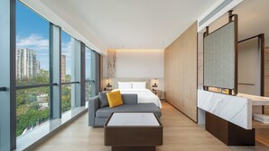 Una habitación de hotel moderna con una cama grande, un sofá, una mesa de centro y un baño con espejo.