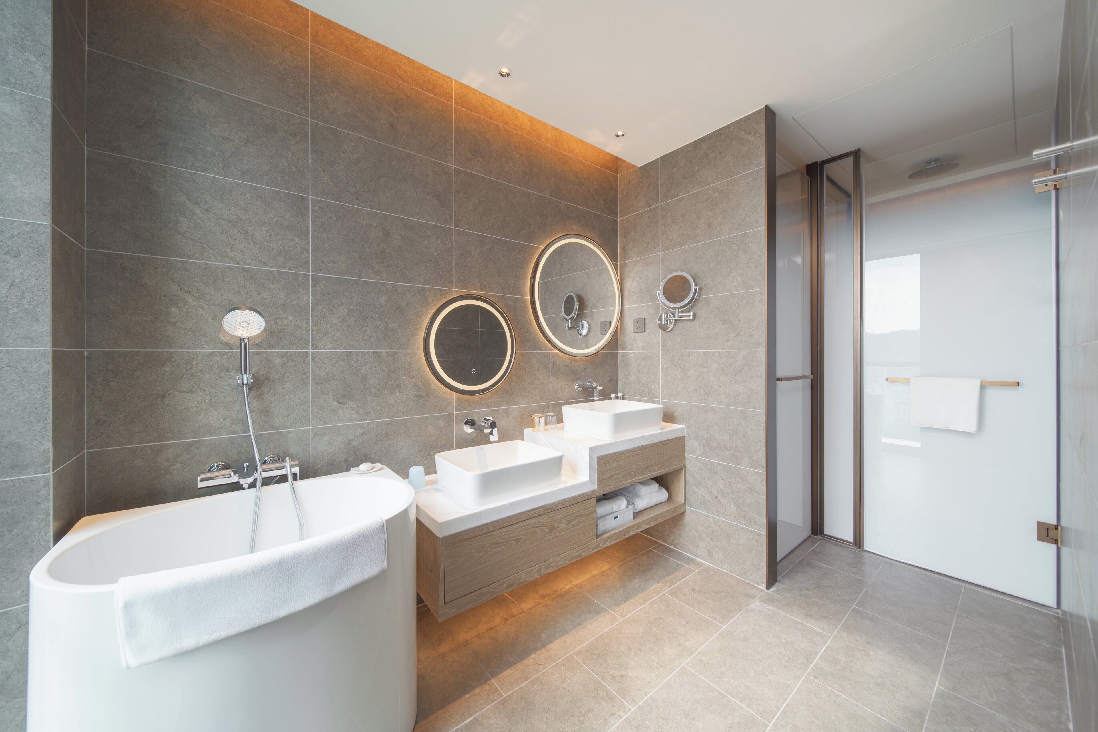 A modern bathroom with a freestanding bathtub, two sinks with mirrors, and a glass shower enclosure.