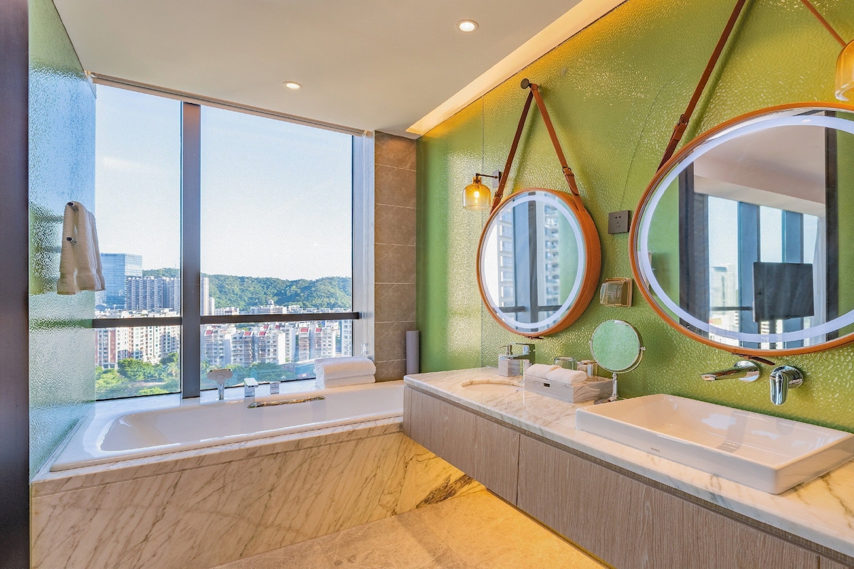 A modern bathroom with two sinks, large mirrors, and a bathtub.