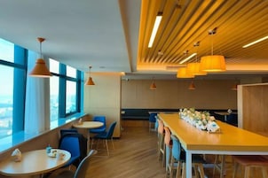 A modern dining area with high ceilings, pendant lighting, and a long communal table.