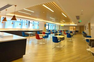 Un área de comedor moderna con una barra alargada y varias mesas y sillas.